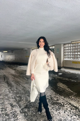 a lady in a white long sweater and a white coat